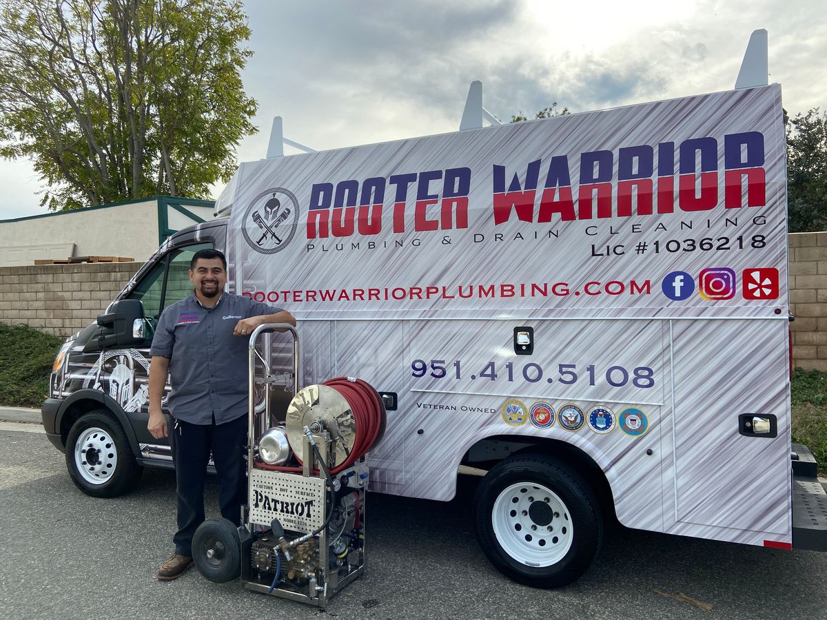 Guillermo of Rooter Warrior with the Patriot hydro-jetter beside a branded service truck