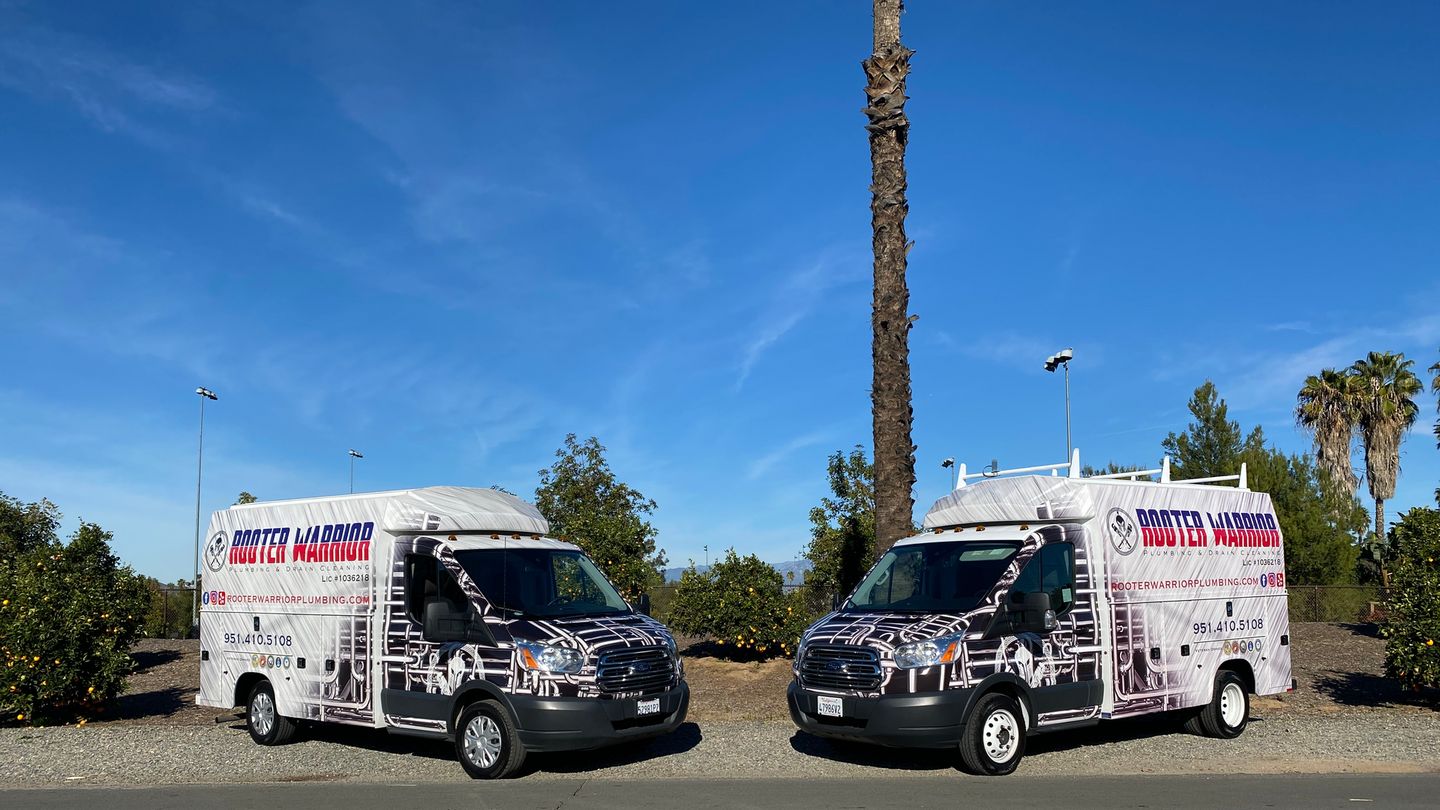Two Rooter Warrior Plumbing service trucks parked side by side
