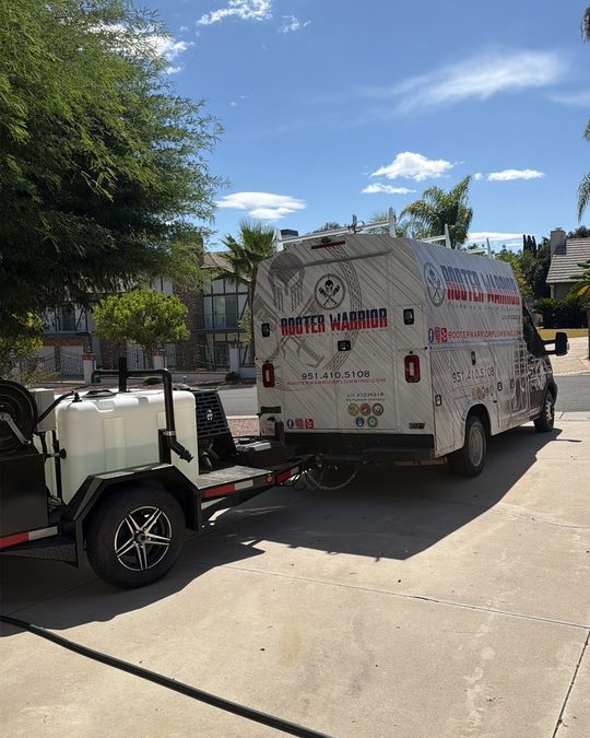 Rooter Warrior service truck towing the company's trailer-mounted hydro jetter in a Riverside-area driveway